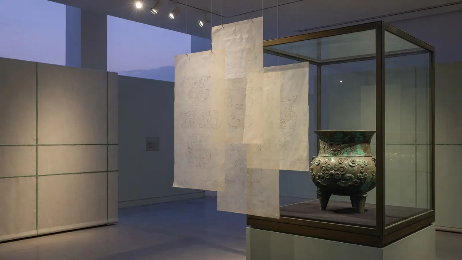 展柜玻璃前悬挂四层半透明硫酸纸，柜内是青铜器
