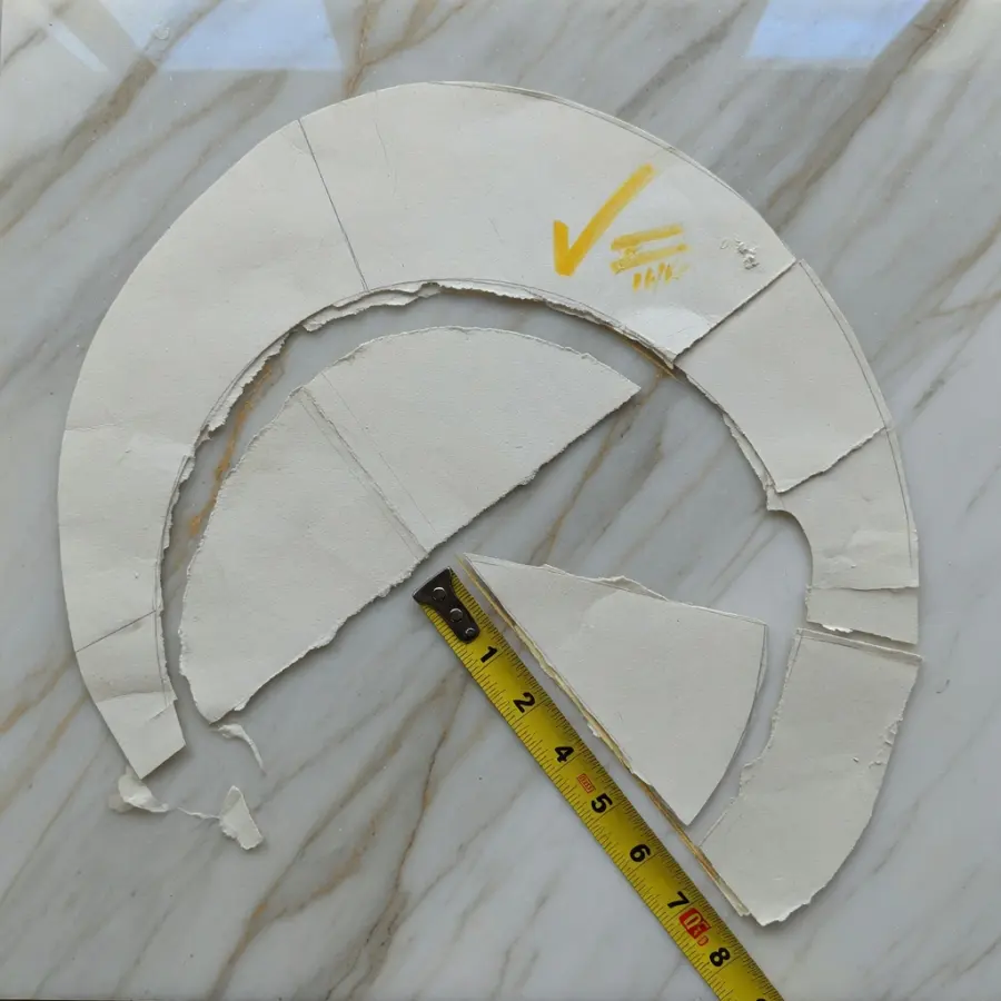 纸样嵌在大理石金灰纹路上，刀缝贴着测量黄边