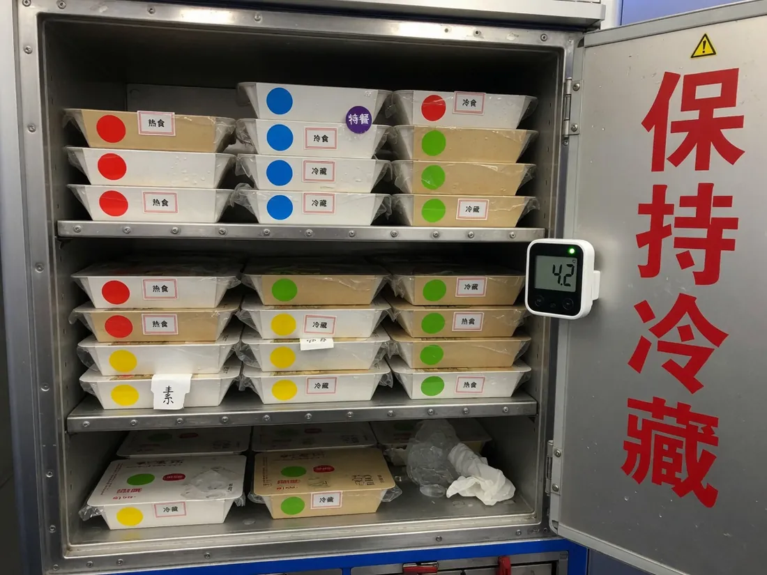 打开的航空餐车：密封餐盒、升舱色标签和温度计
