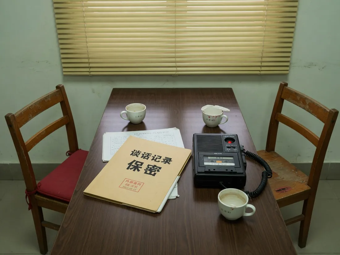 两把椅子与文件夹，录音指示灯关闭的访谈桌